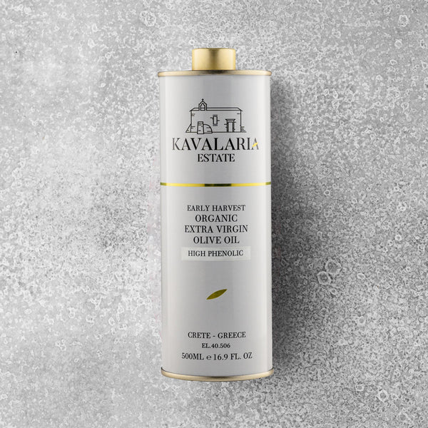 En 500 ml metalbeholder med KAVALARIA ESTATE Økologisk Ekstra Jomfru Olivenolie står oprejst på en struktureret grå overflade og er prydet med et minimalistisk logo i hvidt og guld samt en lille illustration af en bygning fra Kreta.