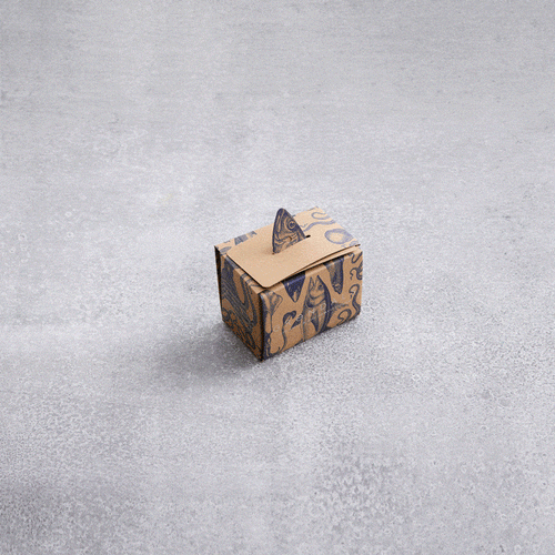 En kompakt Grøndals konserves kube, dekoreret med blå mønstre, hviler på en lysegrå, tekstureret overflade. Den lukkede æske har et håndtag på toppen – en ideel værtsgave for enhver, der værdsætter omtanke i præsentationen.