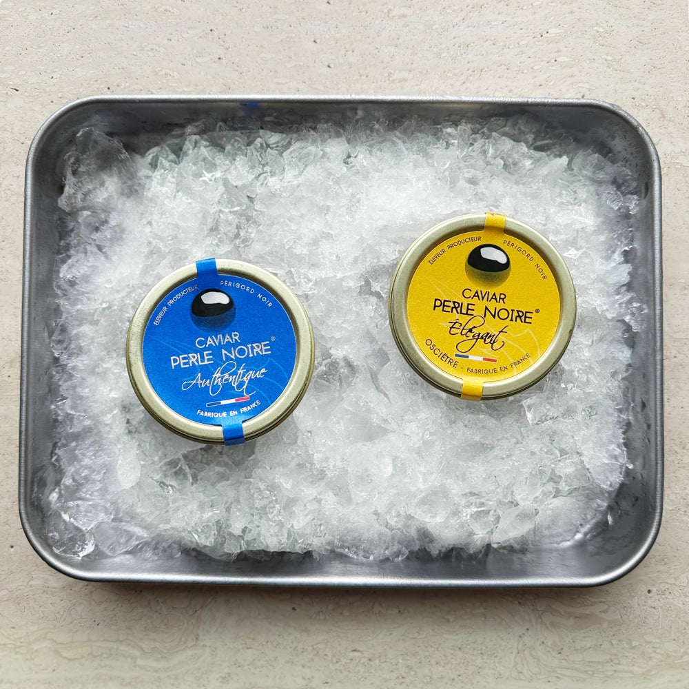 To dåser med Grøndals Kaviar duo - L'Élégant (Oscietre) 30g & L'Authentique (Baerii) 30g - ligger på knust is i en metalbakke, ideel til dem, der nyder luksuskaviar.
