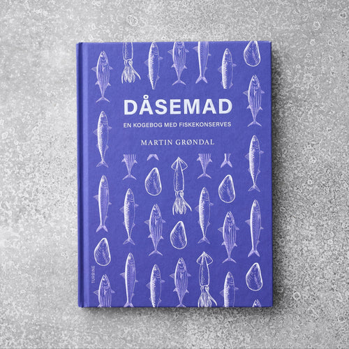 Den lilla kogebog "Kogebogen DÅSEMAD" fra Grøndals viser illustrationer af hvid fisk og skaldyr på omslaget, hvilende på en tekstureret grå overflade.