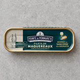 En oval dåse med Pointe de Penmarc’h Makrelfileter, marineret i Sancerre-vin og krydderurter, med en etiket, der viser to kvinder i traditionel dragt og et glas hvidvin.