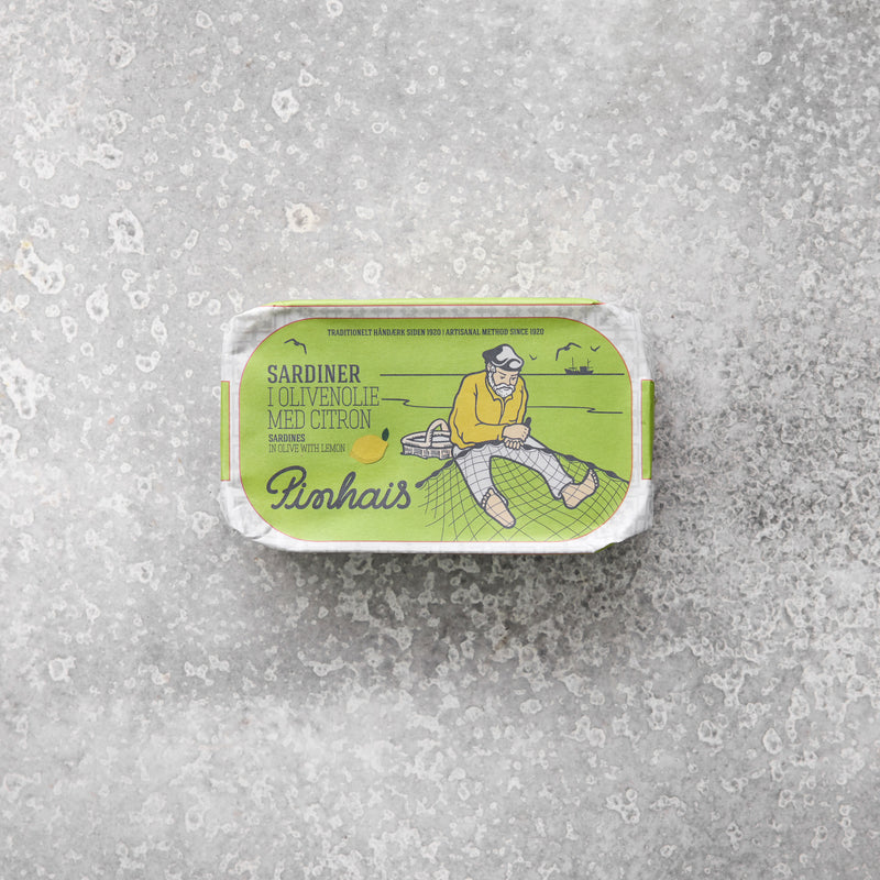 Emballage til Pinhais sardiner i olivenolie med citron fra Grøndals, med en grøn og gul illustration af en fisker, set mod en grå tekstureret baggrund.