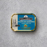 Rektangulær dåse med Pointe de Penmarc’h Sardinfileter med gammeldags sennep med en blå etiket, der viser et fyrtårn og en illustration af to personer.