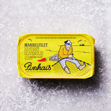En gul dåse Pinhais Makrelfilet i krydret olivenolie med illustration af en fisker på et net og en båd. Dansk og engelsk tekst fremhæver bæredygtigt fiskeri.
