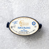 En dåse Grøndals Knivmuslinger i letsaltet lage hviler på en lysegrå tekstureret overflade. Den ovale etiket viser blå og gylden spansk tekst med ingredienser og produktoplysninger.