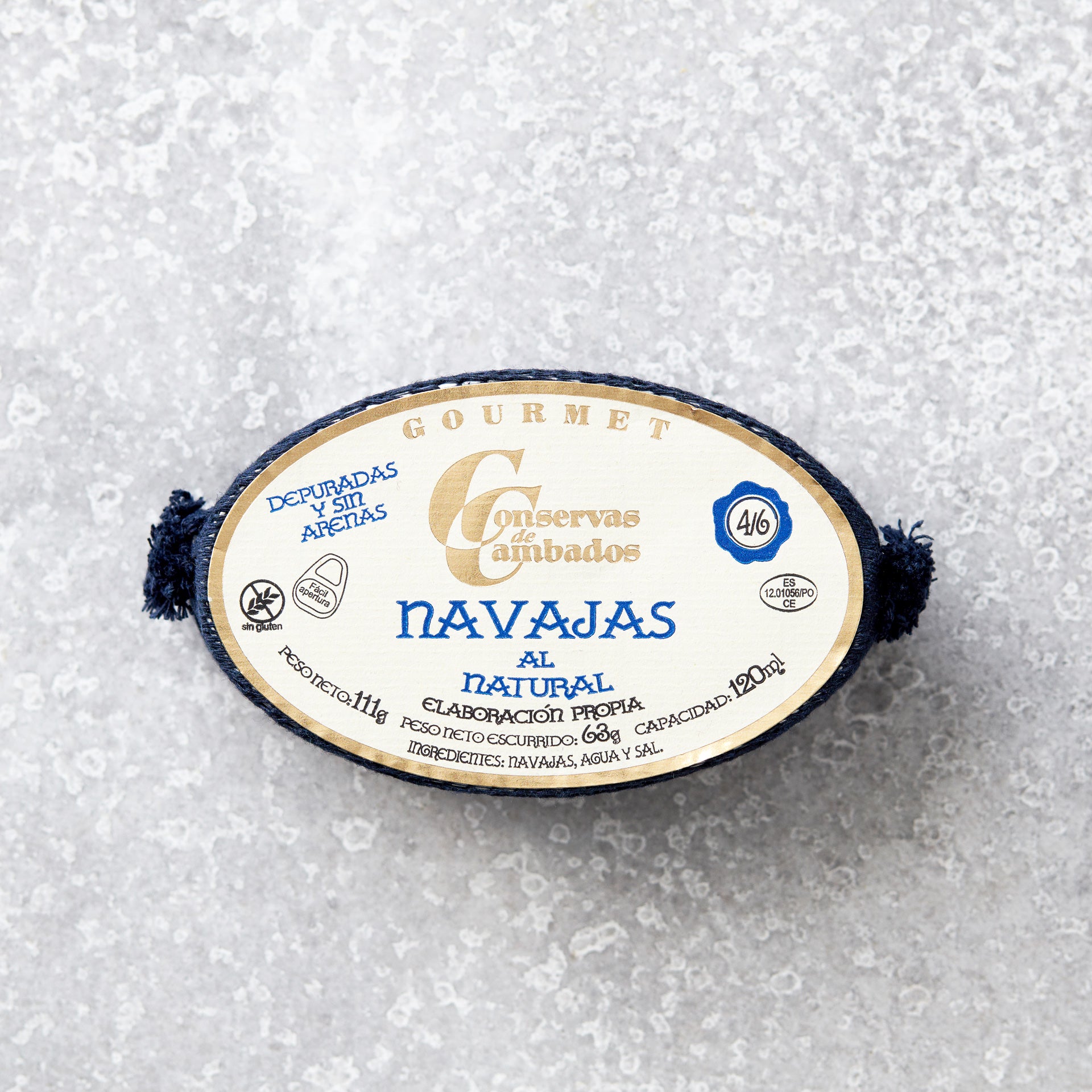 En dåse Grøndals Knivmuslinger i letsaltet lage hviler på en lysegrå tekstureret overflade. Den ovale etiket viser blå og gylden spansk tekst med ingredienser og produktoplysninger.