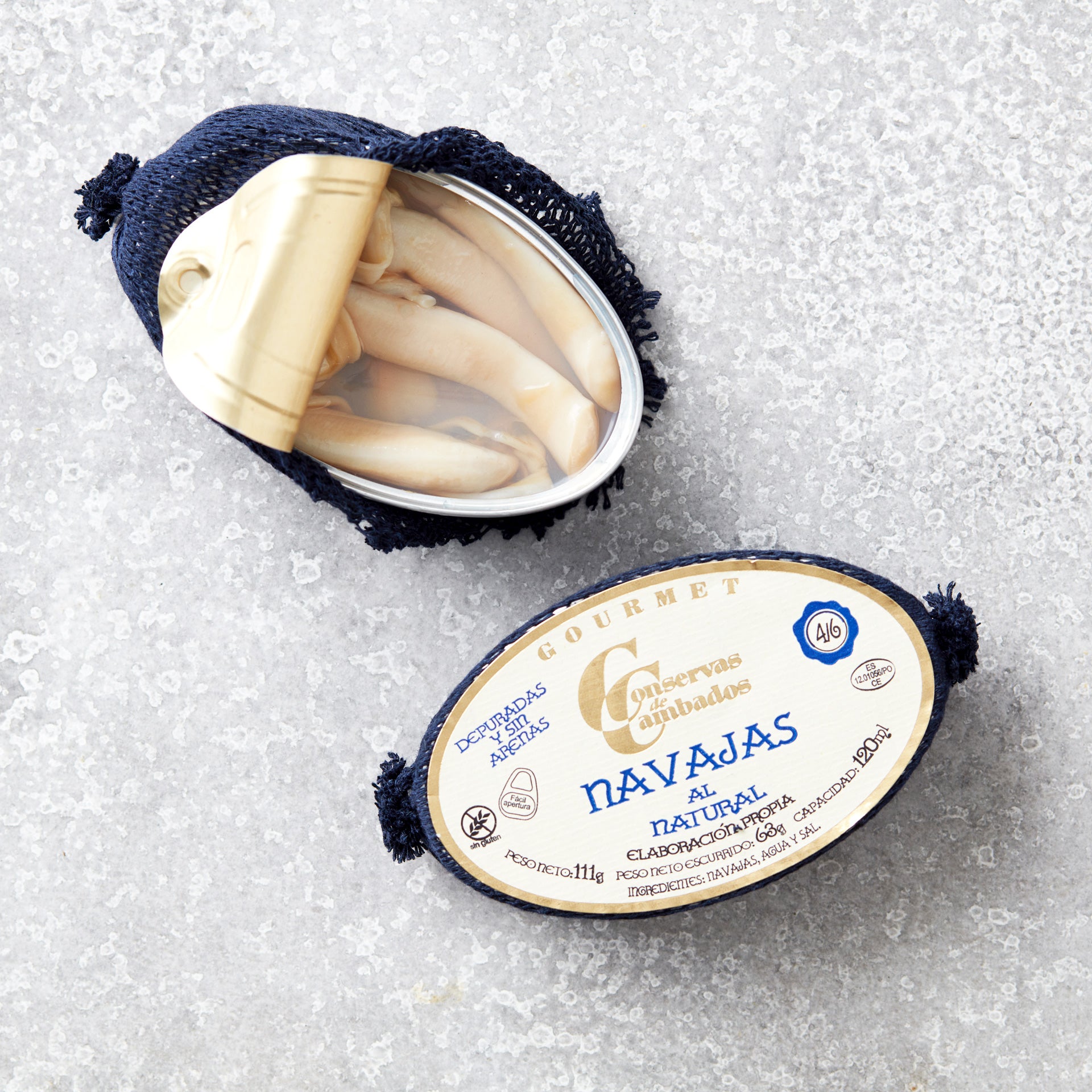 En åbnet oval dåse Grøndals Knivmuslinger i letsaltet lage står på en tekstureret grå overflade, med låget delvist trukket tilbage for at afsløre de gourmet knivmuslinger indeni.