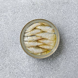 En åben dåse Riga Gold Små brislinger i olivenolie står på en lysegrå, spættet overflade – en sand delikatesse.
